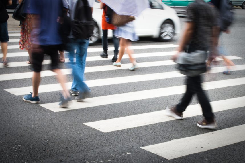 Close up of people crossing a busy city street pedestrian crosswalk zebra crossing