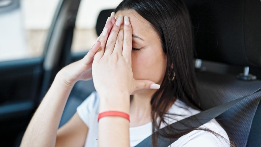 Young anxious woman covering face with hands after car accident