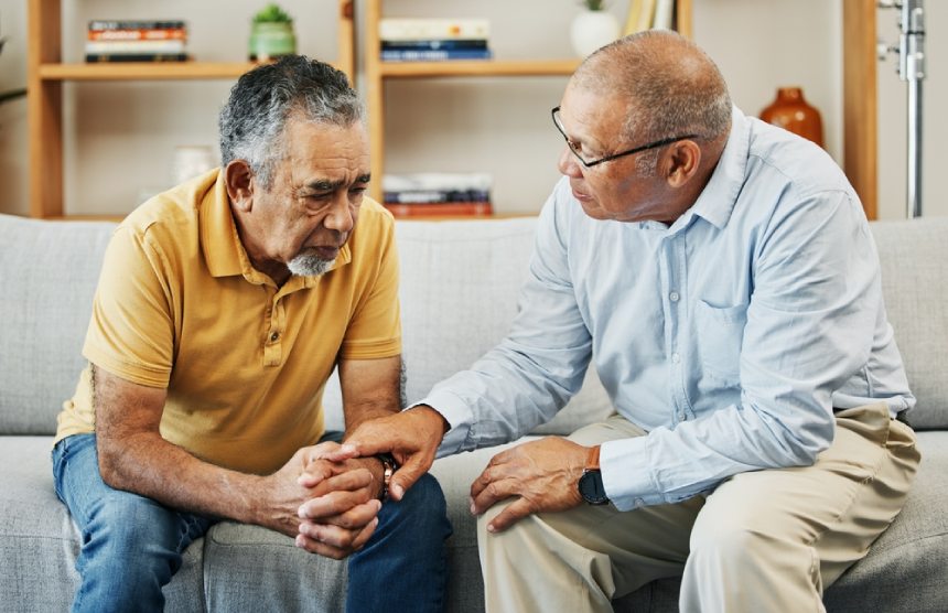 Two friends senior men sitting on sofa offering emotional support