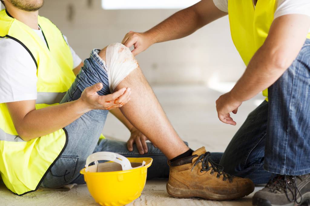 A construction worker being treated on the job for an injured knee