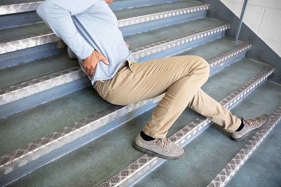 Person lying slumped on staircase clutching their right side after falling down stairs