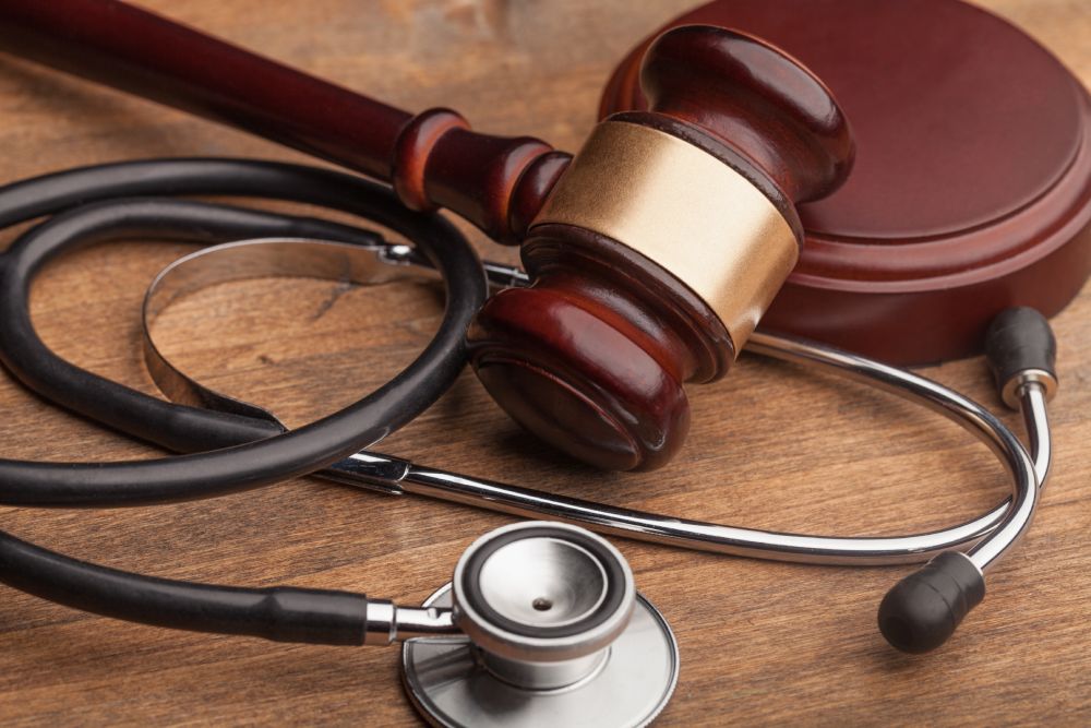 Silver stethoscope and brown gavel on table