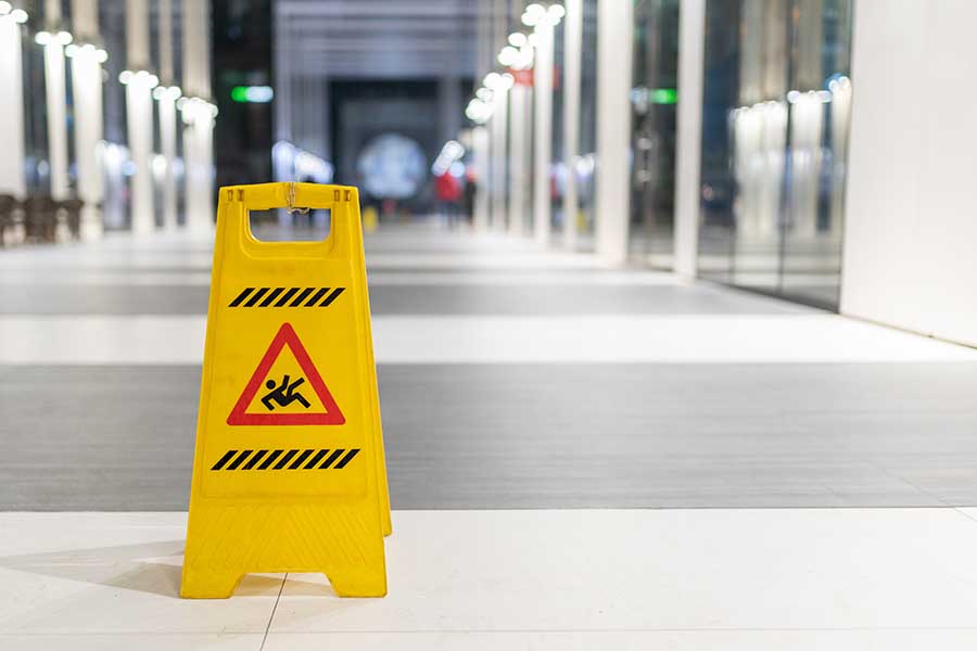Yellow slippery when wet sign on office floor as warning against slips and falls