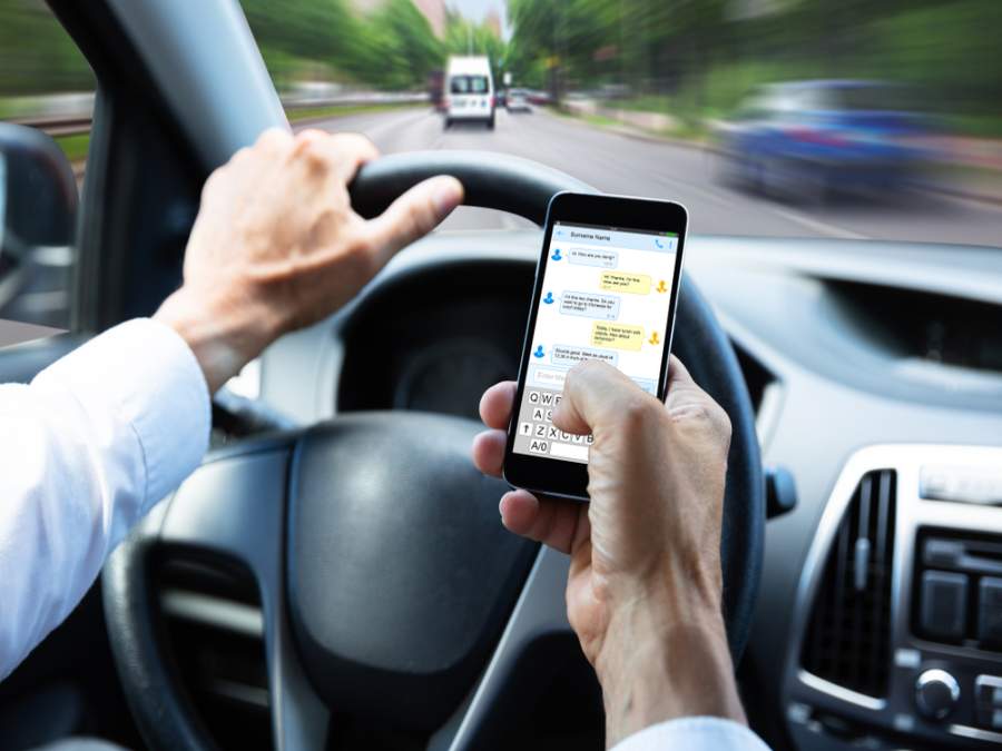 Un hombre enviando mensajes de texto y conduciendo al mismo tiempo