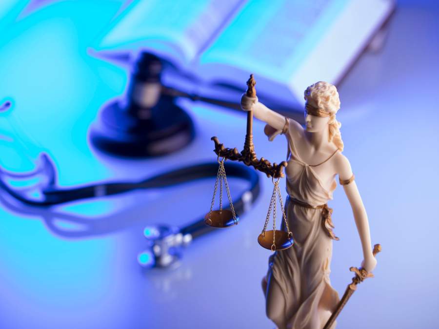 White and gold justice figure with scales and gavel and stethoscope in blue and white background