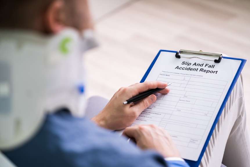 Accident victim with neck brace completing a slip and fall accident claim form on clipboard