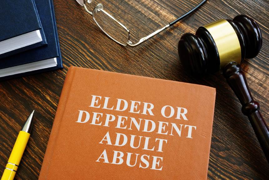Book with elder dependent adult abuse text in white writing and gavel on table