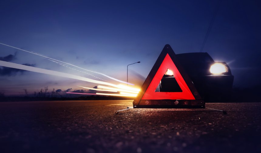 Emergency red triangle stop sign warning car accident car in background at night