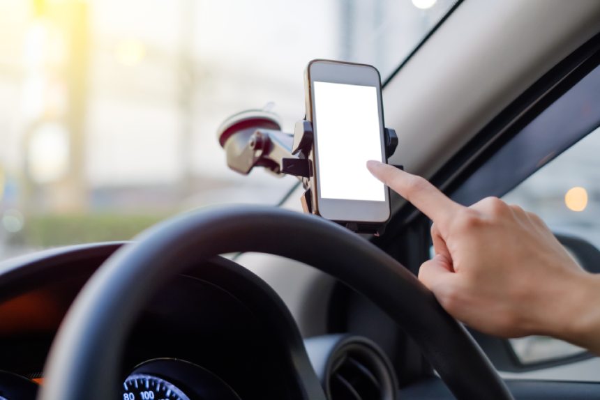 Closeup of rideshare driver’s hand index finger tapping phone screen while driving