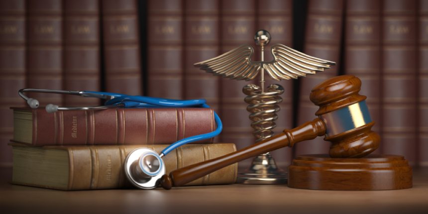 Judges gavel blue stethoscope and brown legal textbooks in front of gold caduceus in library