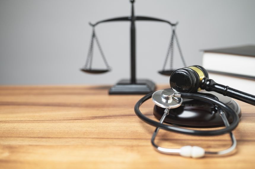 Close up of stethoscope justice scales and law book civil injury claim 