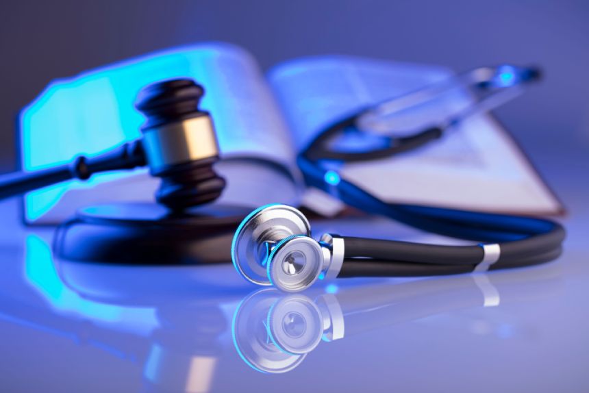 Stethoscope and judges gavel with legal textbook for medical practice claim in background