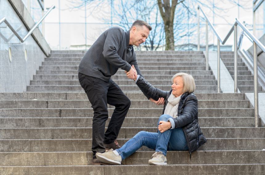 Un hombre ayuda a una mujer a levantarse tras caerse por las escaleras en invierno