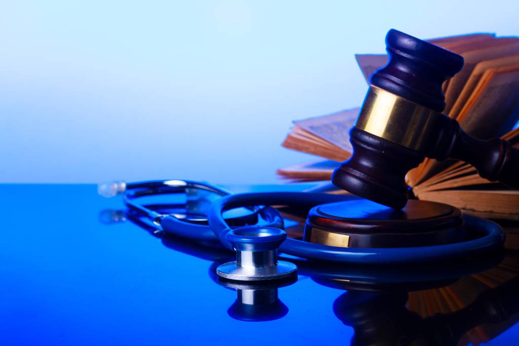 Gavel with legal textbook and stethoscope with blue background medical concept