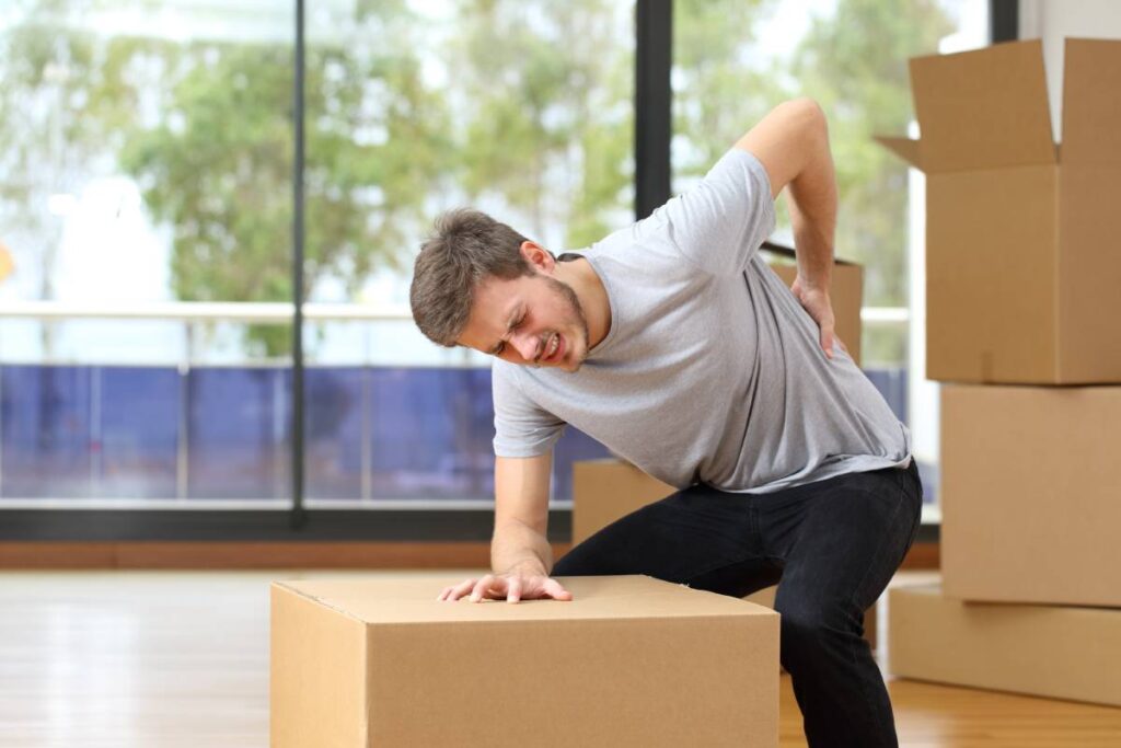 Man clutching back after lifting heavy boxes at work