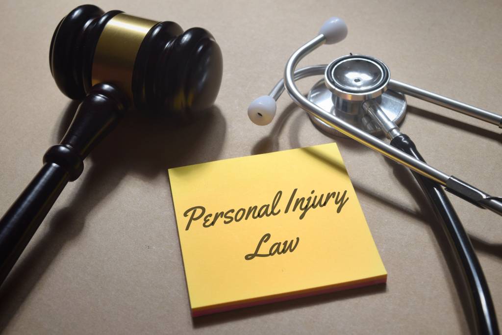 Gavel stethoscope and post-it note with personal injury law in black font