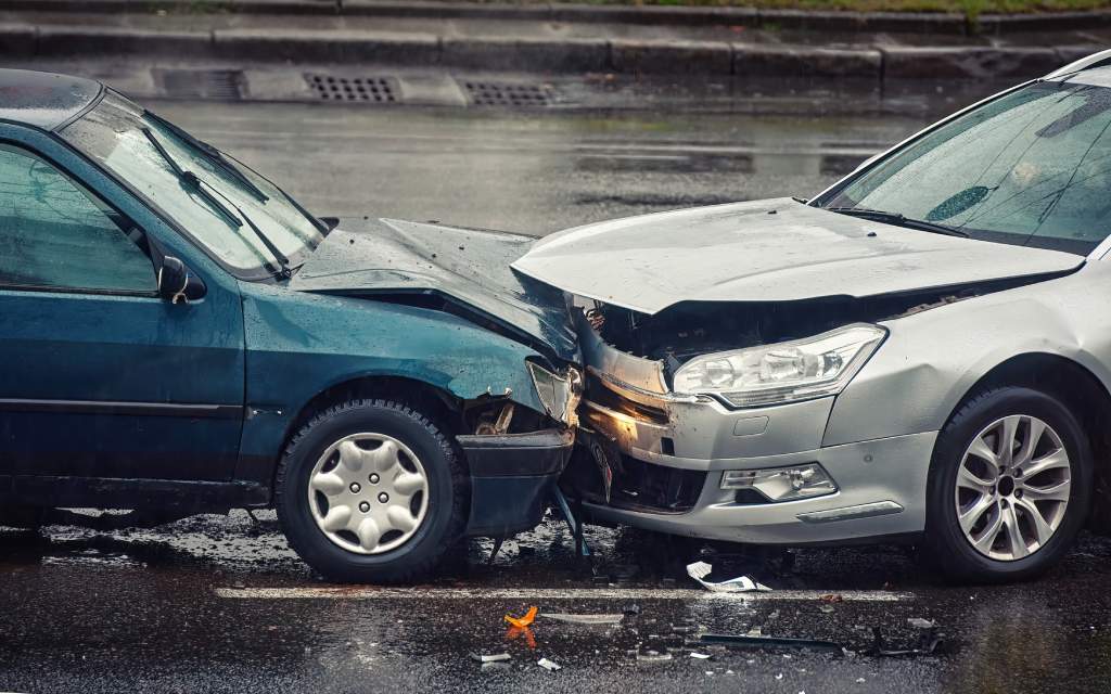 Car accident front collision between two vehicles on wet road during day