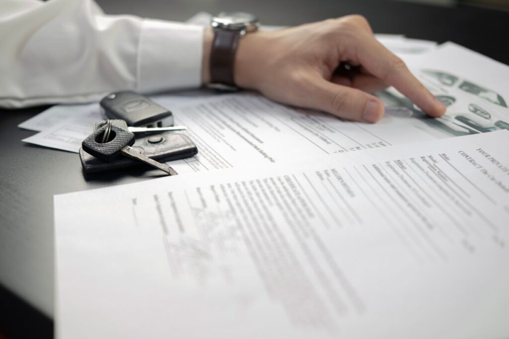 Loss adjuster inspecting car insurance document with keys on table