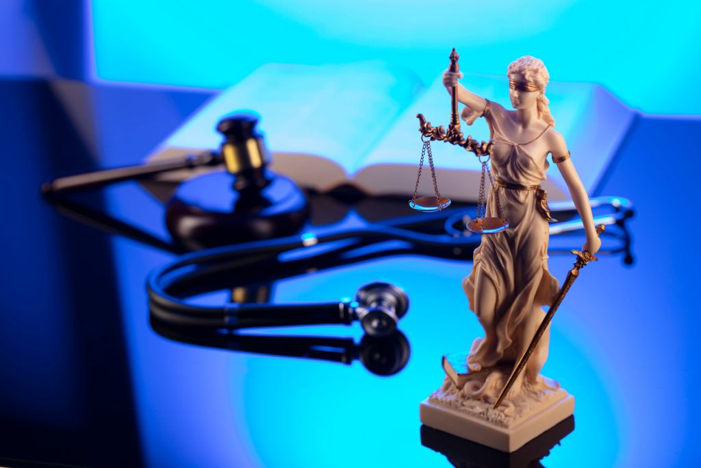 Concept of justice statue and stethoscope against blue background