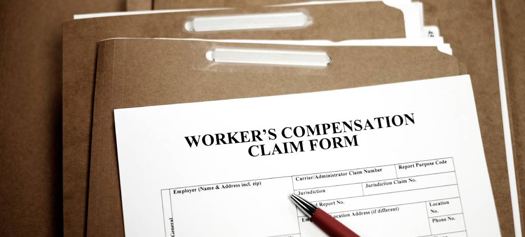 A worker’s claim comp form atop a stack of file folders.