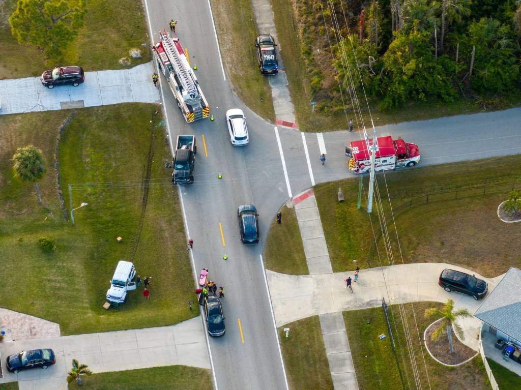Foto aérea de un accidente de tráfico en el que se han visto implicados un coche y una motocicleta, con los servicios de emergencia (bomberos, policía, personal sanitario) en el lugar del accidente.