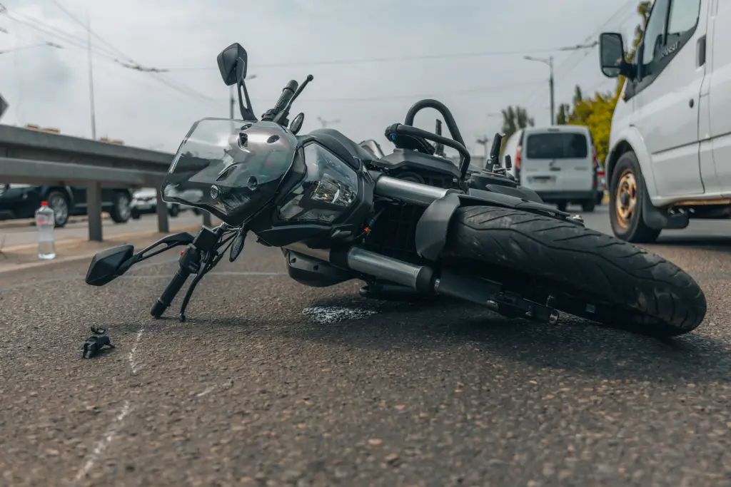 A motorcycle lies on its side in the middle of the highway, damaged but far from totaled.